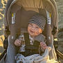 baby, smiling, stroller, beach, sand, blanket, hat, onesie, child, sunlight, outdoor, happy, infant, seatbelt, cozy, cushion, portrait, cute, sunny, warm