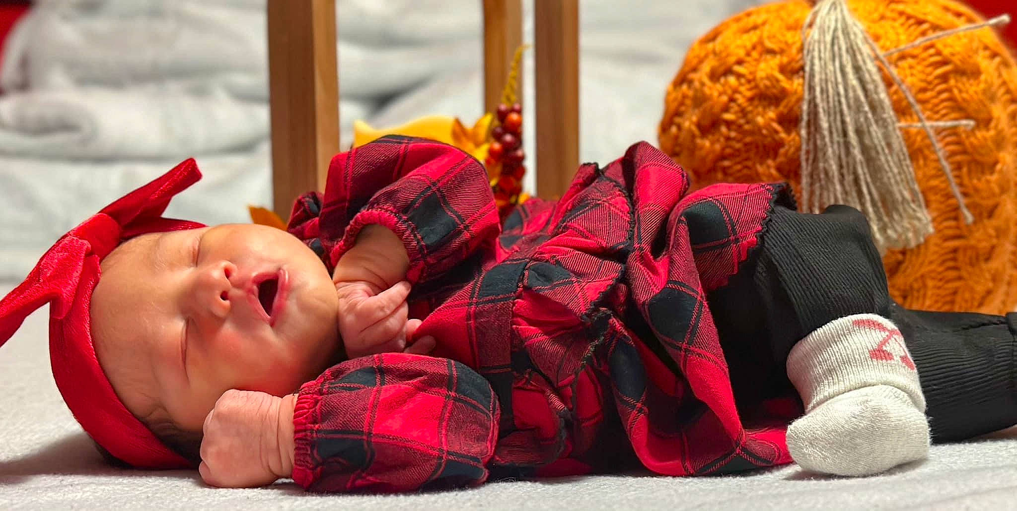 Nayeli is registered to the contest to win money with this photo: art, baby, baby_toddler_clothing, carmine, child, comfort, fashion_accessory, headgear, orange, pattern, person, personal_protective_equipment, plaid, red, room, tartan, textile, toddler, wood, wool