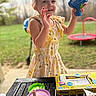 child, girl, toy, bubble_gun, dress, outdoor, table, drink, container, grass, play, happy, smile, face, person, summer, fun, background, nature, lemon_pattern