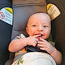 Max is registered to the contest to win money with this photo: baby, infant, car_seat, child, smiling, happy, fingers, blanket, dinosaur_print, seatbelt, warning_label, indoor, cute, portrait, skin, face, head, clothing, safety, young