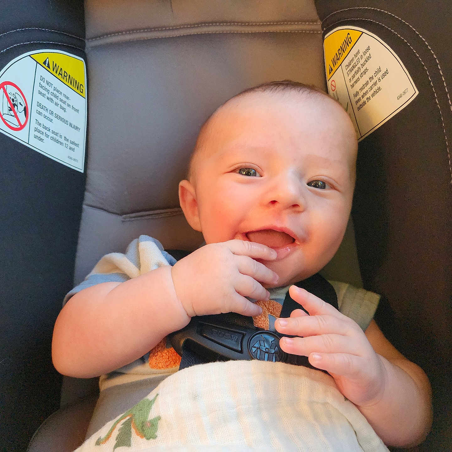 Max is registered to the contest to win money with this photo: baby, child, car_seat, smile, happy, infant, seatbelt, hand, face, clothing, sitting, indoor, cute, young_child, person, head, skin, portrait, seat, safety