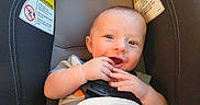 Max is registered to the contest to win money with this photo: baby, car_seat, smiling, infant, hands, blanket, warning_label, child, seatbelt, cute, happy, face, indoor, person, safety, young_child, clothing, head, seat, skin
