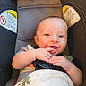 baby, smiling, car_seat, child, infant, blanket, happy, face, hands, cute, seatbelt, indoors, person, young_child, dinosaur_print, cozy, portrait, playful, skin, light