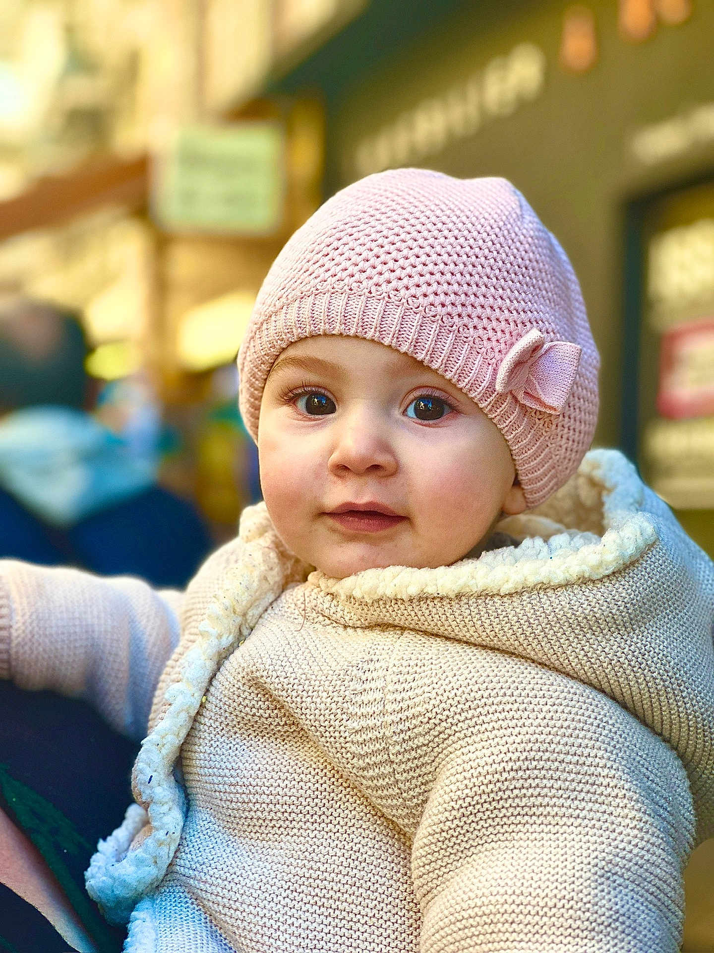 Monika participe au concours pour gagner de l'argent avec cette photo : baby, child, knit_hat, pink_hat, bow, cream_jacket, knit_jacket, face, portrait, outdoor, curious, warm_clothing, person, cute, young_child, urban_background, soft_focus, closeup, winter_wear, innocent