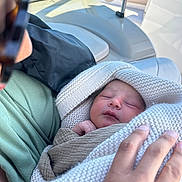 Baker is registered to the contest to win money with this photo: baby, newborn, blanket, knitted, person, hand, boat, water, window, sleeping, wrapped, cozy, adult, cradle, soft, peaceful, closeup, indoors, gentle, tender