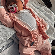 Naiari is registered to the contest to win money with this photo: baby, blanket, child, cozy, cute, hat, hoodie, hospital_bed, indoors, infant, newborn, pacifier, pajamas, pink_clothing, relaxing, sleep, sleeping, soft_light, striped_socks, white_clothing