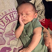 Miles Young joined the competition — help win amazing prizes! baby, infant, sleeping, child, portrait, close_up, indoors, blanket, onesie, green_clothing, adult, parent, hand, cheek, cozy, resting, bed, home, candid, family