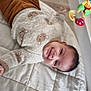 baby, smile, sweater, teddy_bear, blanket, toy, infant, child, cute, indoor, soft, warm, cozy, happy, lying_down, playful, face, person, head, clothing
