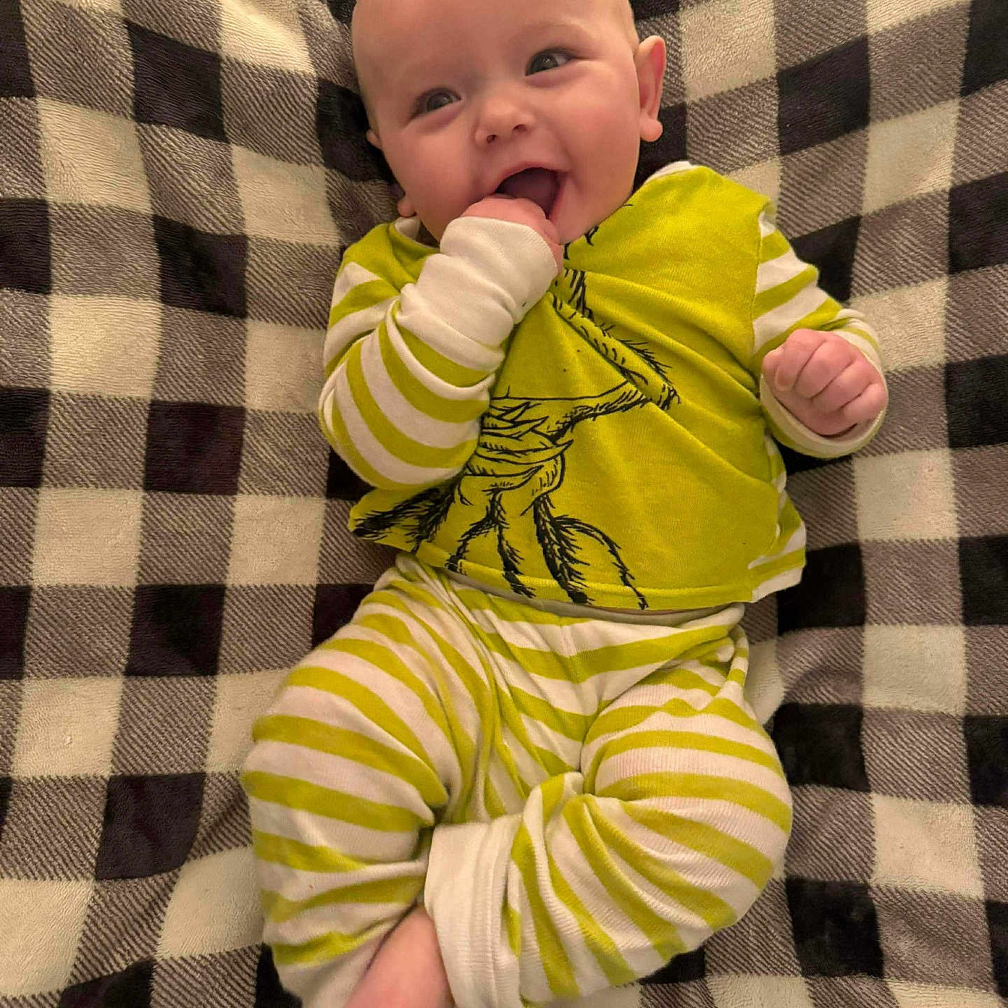 Miles is registered to the contest to win money with this photo: baby, infant, smiling, striped_clothing, green, white, blanket, checkered, cute, happy, lying_down, face, hand, foot, pajamas, child, indoors, cozy, playful, portrait