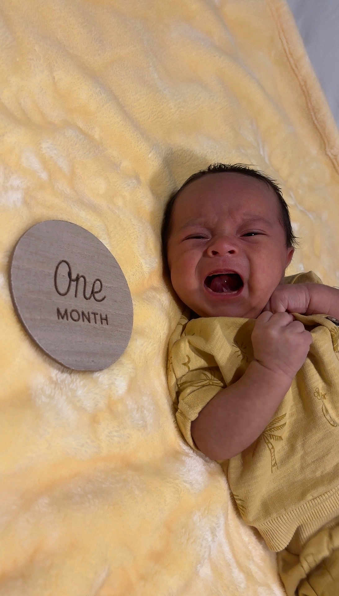 Aram joined the competition — help win amazing prizes! baby, newborn, crying, infant, yellow_blanket, wooden_sign, one_month, clenched_fist, lying_down, soft_texture, milestone, closeup, person, face, expression, cute, indoors, wearing_clothes, skin, small