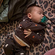 Oakley is registered to the contest to win money with this photo: baby, sleeping, pacifier, blanket, leopard_print, pajamas, infant, portrait, indoors, cozy, lying_down, resting, peaceful, soft_lighting, textile, clothing, barefoot, bed, nap, cute