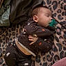 baby, sleeping, pacifier, blanket, leopard_print, pajamas, infant, portrait, indoors, cozy, lying_down, resting, peaceful, soft_lighting, textile, clothing, barefoot, bed, nap, cute