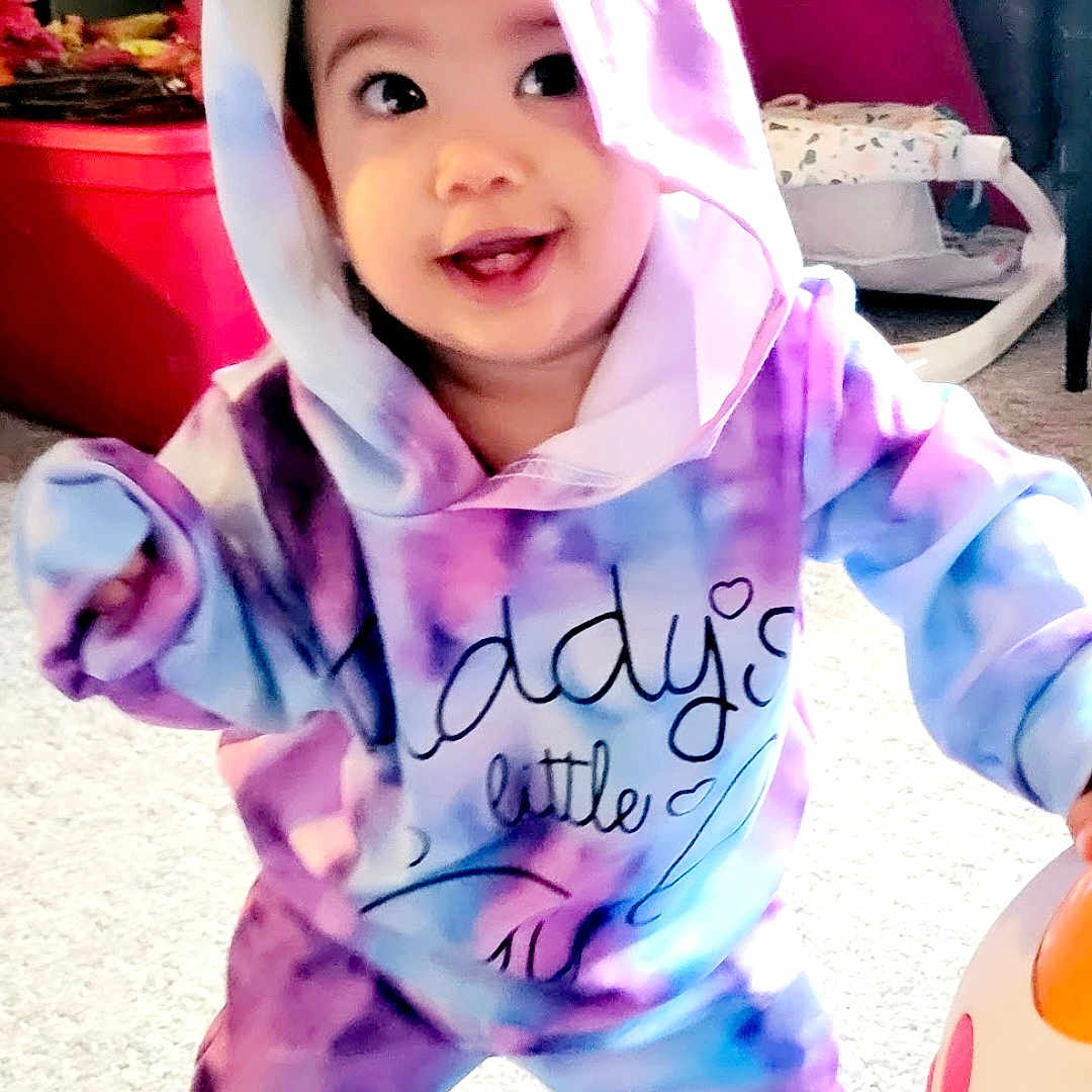 Sophie is registered to the contest to win money with this photo: baby, bonnet, cap, clothing, coat, costume, face, hat, head, hood, hoodie, jacket, knitwear, pajamas, person, photography, portrait, purple, sweater, sweatshirt
