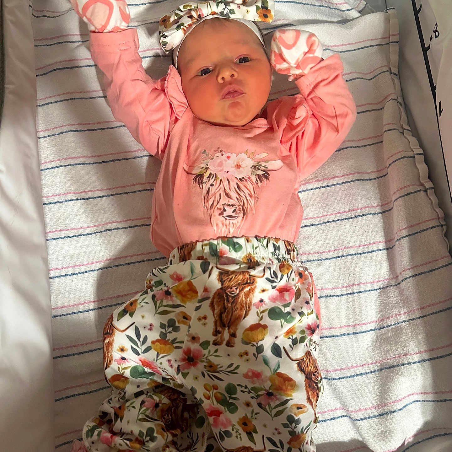 Jessie joined the competition — help win amazing prizes! baby, infant, child, portrait, lying_down, crib, blanket, floral_clothing, pink_outfit, mittens, headband, bow, face, eyes_open, indoor, nursery, bedding, striped_blanket, happy, safe