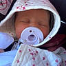 newborn, baby, sleeping, pacifier, hood, blanket, floral_pattern, car_seat, infant, portrait, close_up, face, eyes_closed, bundled, pink, white, cozy, travel, child, peaceful