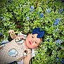 baby, child, blue_bow, headband, flowers, greenery, outdoor, nature, plants, foliage, grass, cute, infant, smiling, happy, skin, hand, dress, lying_down, spring