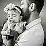 Azalea is registered to the contest to win money with this photo: baby, child, man, pacifier, headband, flower, beard, holding, sleeping, indoor, black_and_white, portrait, love, family, closeup, affection, watch, tattoo, gentle, calm