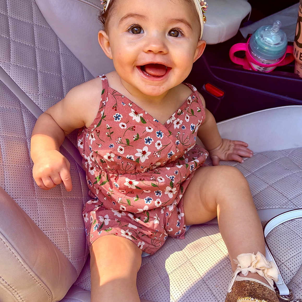Azalea is registered to the contest to win money with this photo: accessory, baby, baby_shoes, car_interior, car_seat, child, cute, dress, flower_pattern, footwear, happy, headband, indoors, infant, leather_seat, one_person, portrait, sitting, smiling, young_child