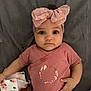 baby, infant, headband, pink, bow, clothing, lying_down, blanket, cute, child, face, expression, hand, fabric, floral, pajamas, person, skin, indoors, portrait