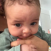 Lyana a rejoint le concours — aidez-le/la à gagner de superbes lots ! baby, child, hand, face, curly_hair, green_sweater, indoor, person, skin, closeup, nibbling, infant, adult_hand, holding, expression, cute, soft_light, portrait, human, toddler