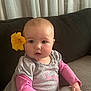 Arabella is registered to the contest to win money with this photo: baby, flower, child, pink_clothing, grey_clothing, sitting, indoor, couch, curious, face, young_child, portrait, cute, soft_lighting, baby_girl, hand, looking, love_text, yellow_flower, home