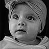 baby, child, black_and_white, portrait, head_wrap, bow, knitwear, soft_texture, close_up, curious_look, infant, face, eyes, expression, studio_lighting, cozy, cute, young_child, monochrome, innocence