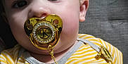 Kadien joined the competition — help win amazing prizes! accessory, baby, chain, child, close_up, clothing, cute, face, gold, indoors, infant, lying_down, mouth, pacifier, person, portrait, skin, striped_shirt, texture, yellow