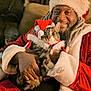 Sasha is registered to the contest to win money with this photo: beard, cat, christmas, costume, cozy, cute, dreadlocks, festive, furry, holding, holiday, indoor, man, pet, portrait, red_clothing, santa_hat, smile, warm_lighting, white_fur_trim