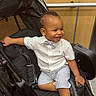 toddler, child, smiling, stroller, indoor, clothing, bow_tie, shorts, shoes, happy, person, baby, seat, wheel, black, white_shirt, striped, cute, portrait, furniture
