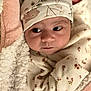 baby, infant, face, hat, blanket, clothing, floral_pattern, cozy, cute, newborn, soft, sleepwear, child, portrait, indoors, warm, toddler, apparel, resting, young
