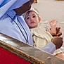 baby, nun, church, pew, wooden_bench, woman, child, indoor, religious, holding, tenderness, light, people, seated, portrait, clothing, headwear, face, expression, care