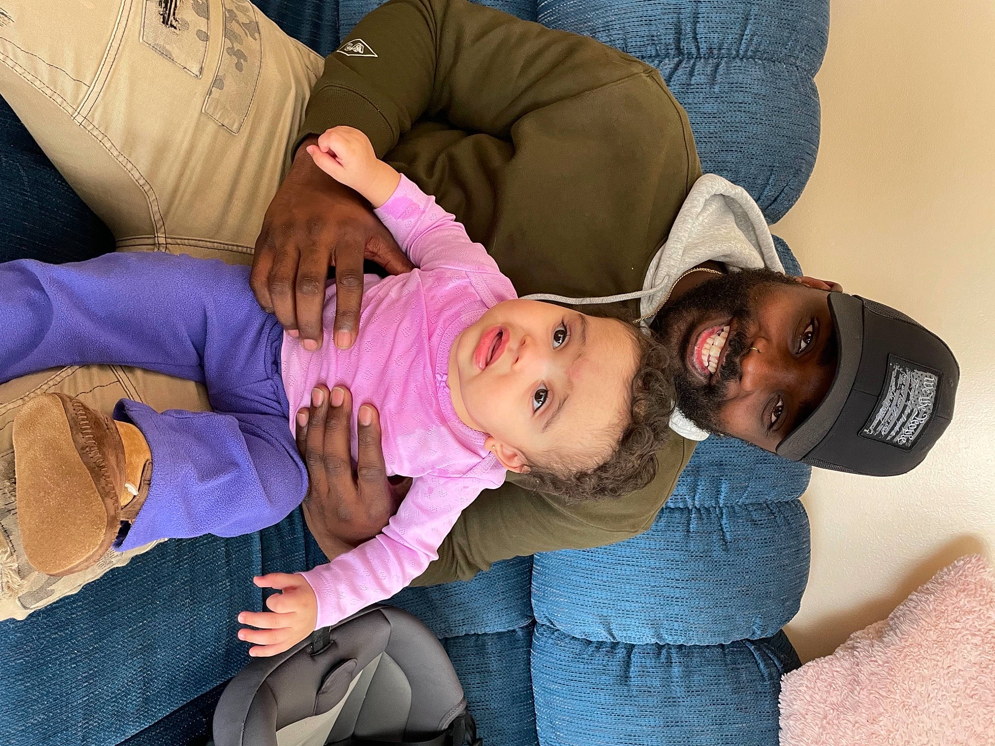 Emeri is registered to the contest to win money with this photo: arm, clothing, comfort, dress, finger, fun, gesture, hand, happy, hat, headwear, interaction, joint, joy, lap, leg, mouth, person, purple, skin