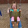 toddler, child, swing, playground, doll, toy, happy, smiling, outdoor, woodchips, brick_wall, casual_clothing, sneakers, blue_jeans, green_shirt, playtime, person, young_child, daylight, fun