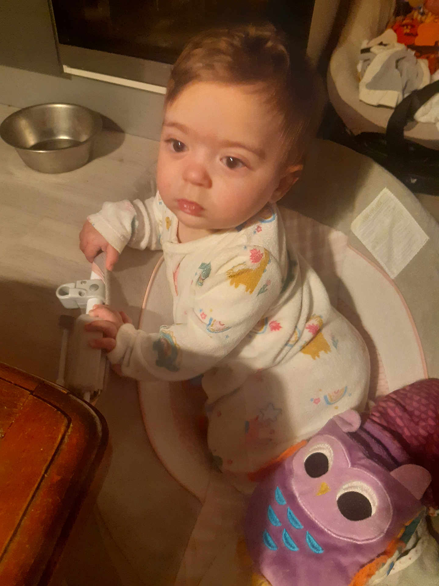 Inaya participe au concours pour gagner de l'argent avec cette photo : baby, infant, pajamas, toy, owl_toy, indoor, child, person, face, hand, wooden_table, floor, play_area, curious, grip, furniture, home, cozy, dim_lighting, soft_toy