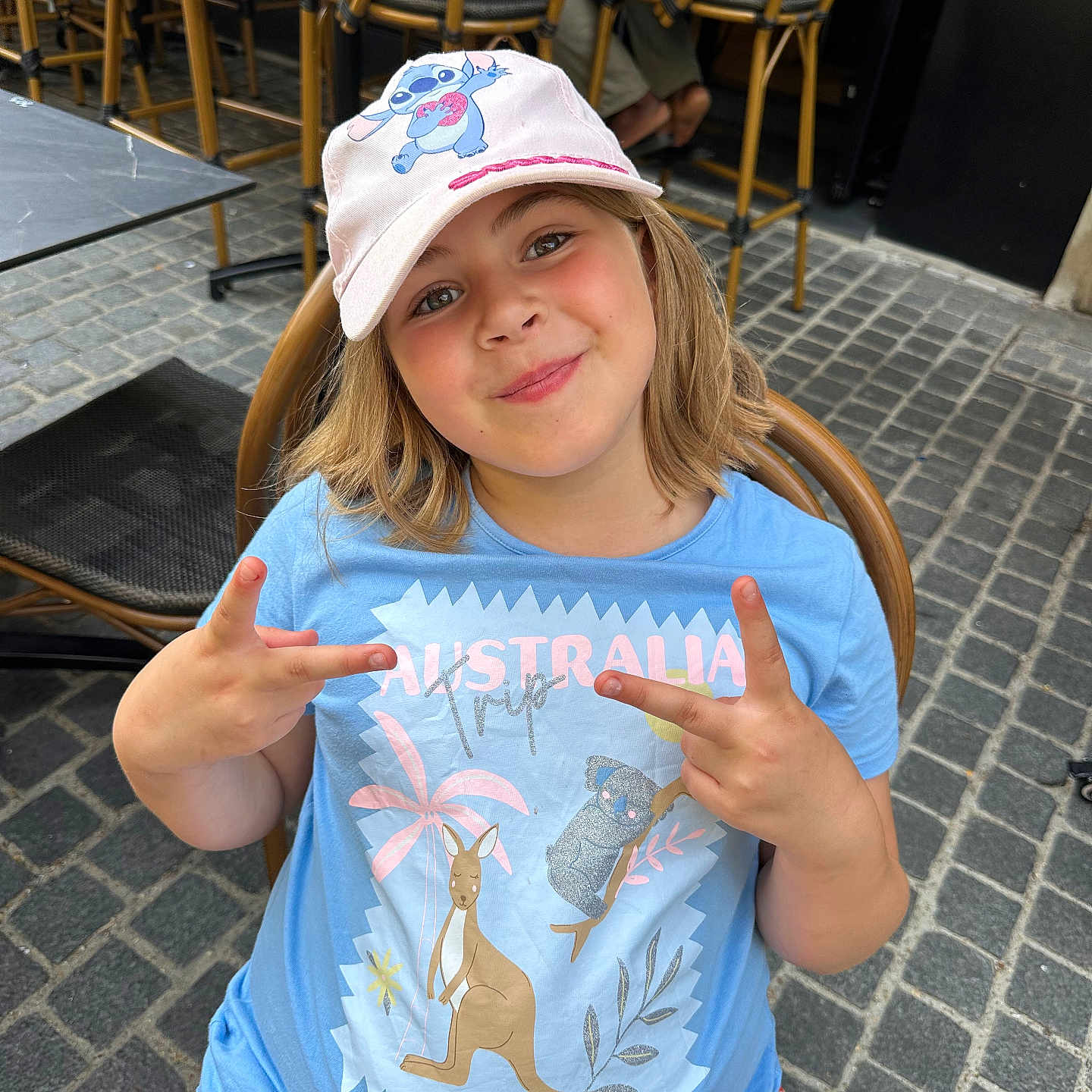 Tyméa a rejoint le concours — aidez-le/la à gagner de superbes lots ! australia, blue_shirt, cafe, cap, casual_clothing, chair, child, cobblestone, girl, happy, hat, kangaroo, koala, outdoor, pavement, peace_sign, person, playful, smile, summer