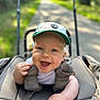 baby, baby_seat, blue_eyes, cap, child, clothing, cute, daylight, face, greenery, hand, happy, infant, nature, outdoor, pathway, portrait, smiling, stroller, sunlight