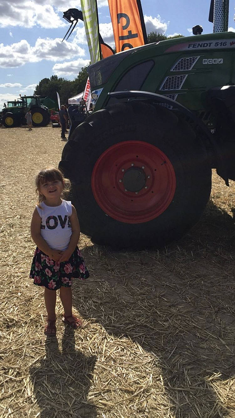 Elvy a rejoint le concours — aidez-le/la à gagner de superbes lots ! agricultural_machinery, asphalt, auto_part, automotive_exterior, automotive_tire, automotive_wheel_system, bumper, farmer, fun, grass, joy, motor_vehicle, person, rolling, sky, tire, toddler, travel, tread, tree