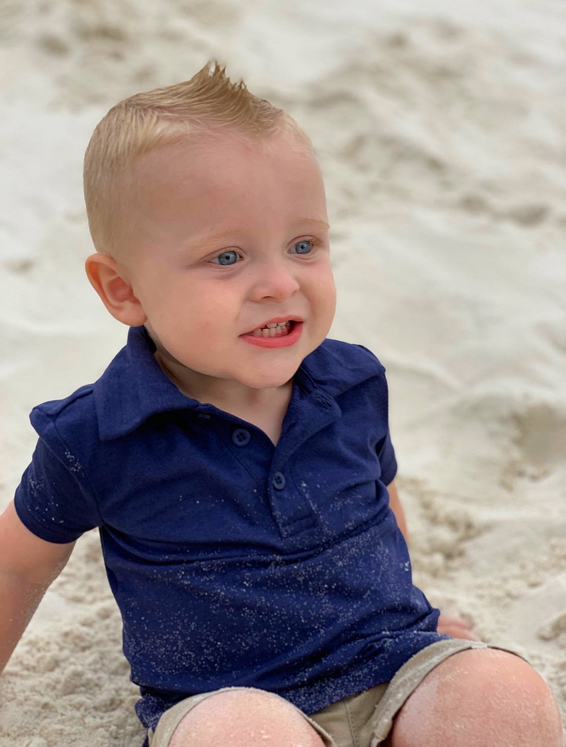 Briggs is registered to the contest to win money with this photo: baby, beach, blond, cheek, child, eye, face, head, human, leg, person, photography, play, sand, sea, sitting, skin, smile, summer, toddler