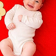 Sophia is registered to the contest to win money with this photo: baby, baby_girl, child, cute, expression, face, feet, hands, happy, headband, indoors, infant, lying_down, one_person, portrait, red_blanket, red_bow, skin, smiling, white_onesie