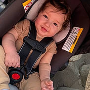 Jayceon joined the competition — help win amazing prizes! baby, child, car_seat, safety_harness, smile, face, hands, clothing, curly_hair, rosy_cheeks, infant, seatbelt, warning_label, outdoor, cute, person, closeup, toddler, seat, soft_lighting