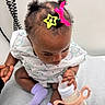 Vanessa joined the competition — help win amazing prizes! baby, infant, child, bottle, socks, hair_clips, medical_gown, hospital, exam_table, hand, person, sitting, curious, indoors, cute, feeding, holding, skin, head, clothing
