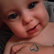 Grayson is registered to the contest to win money with this photo: baby, child, face, blue_eyes, hand, tattoo, heart, skin, close_up, expression, person, cute, indoor, infant, human, portrait, holding, love, toddler, chubby_cheeks