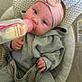 baby, bottle, headband, clothing, seat, infant, feeding, pink, gray, hand, face, cushion, pattern, indoor, closeup, portrait, cozy, child, sitting, bottle_feeding