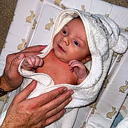 Albie joined the competition — help win amazing prizes! baby, towel, hands, changing_pad, bunny_pattern, infant, skin, hooded_towel, carpet, person, newborn, cute, wrapped, soft, bedroom, child, comfort, care, indoors, portrait