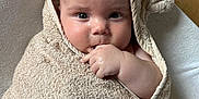 Kayce a rejoint le concours — aidez-le/la à gagner de superbes lots ! baby, towel, hood, bear_ears, hand, fingers, face, skin, curious, child, infant, wrapped, cushion, white, floor, tile, cute, indoors, portrait, soft
