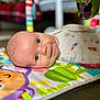 Kayce a rejoint le concours — aidez-le/la à gagner de superbes lots ! baby, infant, play_mat, colorful, smiling, face, head, eyes, clothing, soft_toys, indoor, child, cute, young, portrait, lying_down, focus, blurred_background, skin, expression