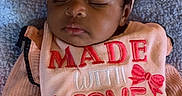 Genesis is registered to the contest to win money with this photo: adorable, baby, bib, blanket, bow, child, close_up, cozy, cute, headband, indoor, infant, peaceful, pink_clothing, portrait, resting, sleeping, soft_lighting, textile, young_child