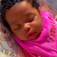 Genesis is registered to the contest to win money with this photo: baby, sleeping, curly_hair, pink_bib, infant, close_up, cute, child, resting, cozy, portrait, soft_lighting, indoors, animal_pattern, baby_seat, peaceful, young_child, face, cute_expression, toddler