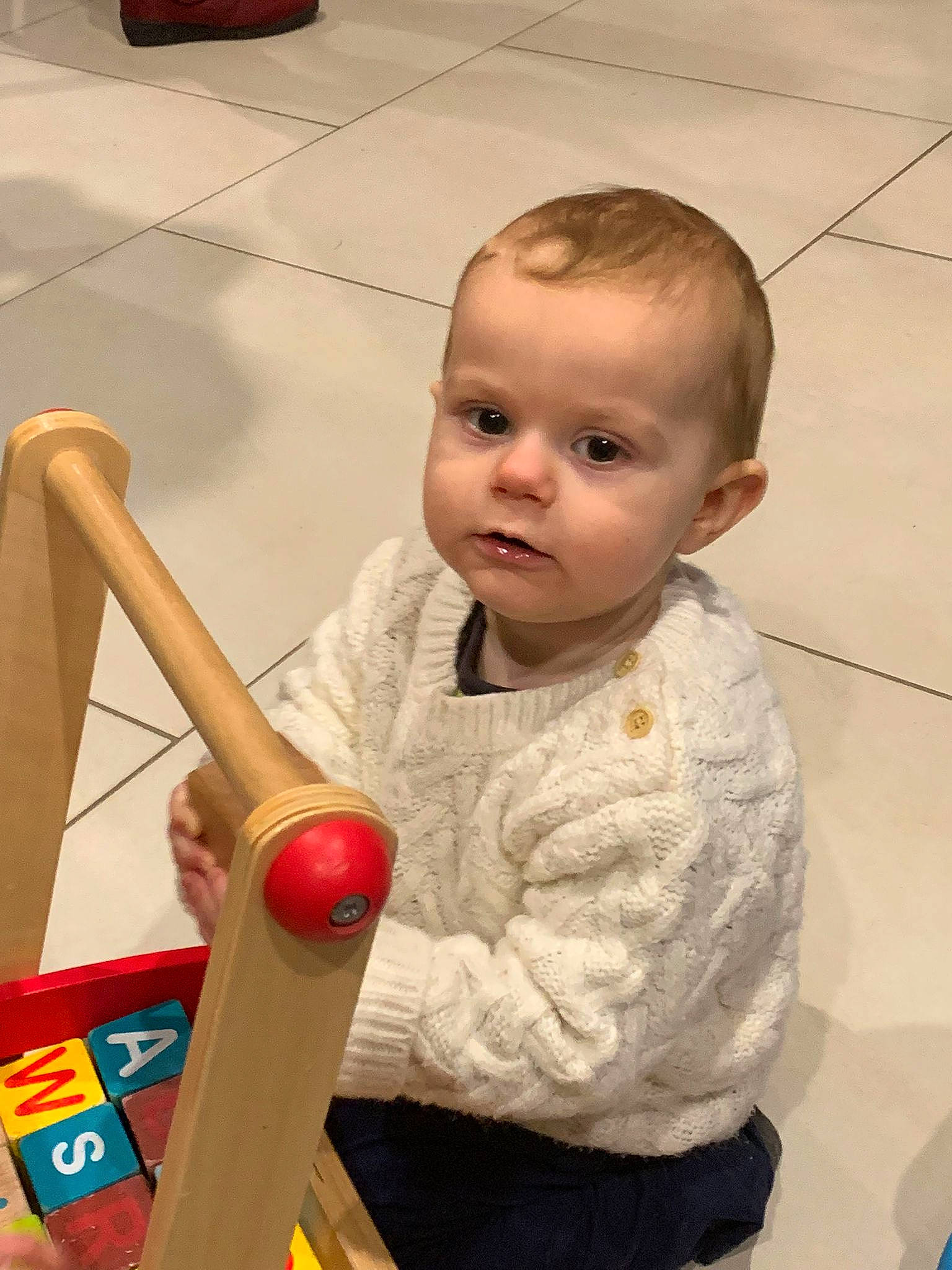 Hayden a rejoint le concours — aidez-le/la à gagner de superbes lots ! baby, baby_playing_with_toys, baby_products, baby_toddler_clothing, baby_toys, cheek, child, flooring, fun, hardwood, nose, person, play, room, sitting, t_shirt, toddler, toy, wood