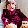 baby, infant, knit_hat, pom_pom, maroon_clothing, cozy, booties, white_blanket, cute, smiling, playful, indoor, portrait, child, warm_clothing, funny_face, soft_texture, toddler, happy, person